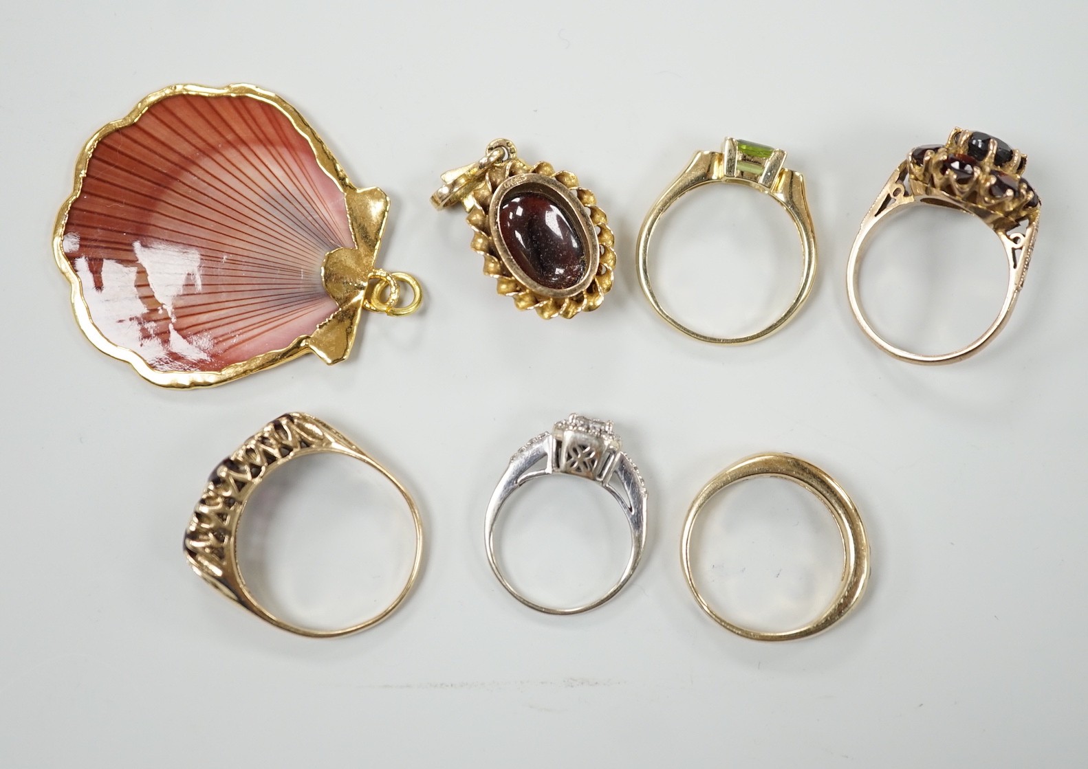 A 9ct and garner cluster set dress ring, size M, gross 4.9 grams, two yellow or white metal and diamond set rings, including half eternity and a yellow metal and garnet set half hoop ring, gross 8.8 grams, a 14k, single